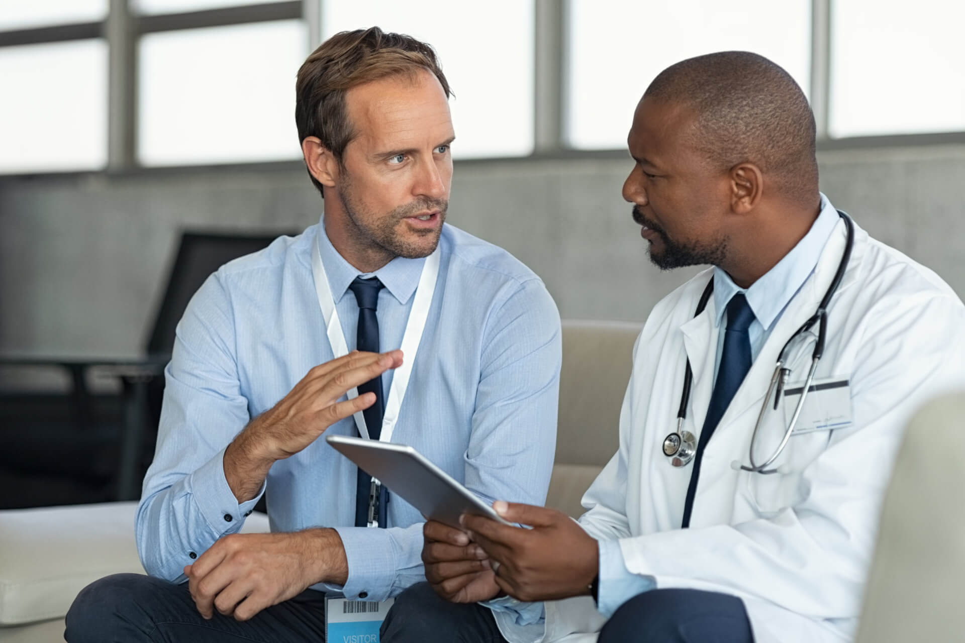 two healthcare professionals speaking over a tablet